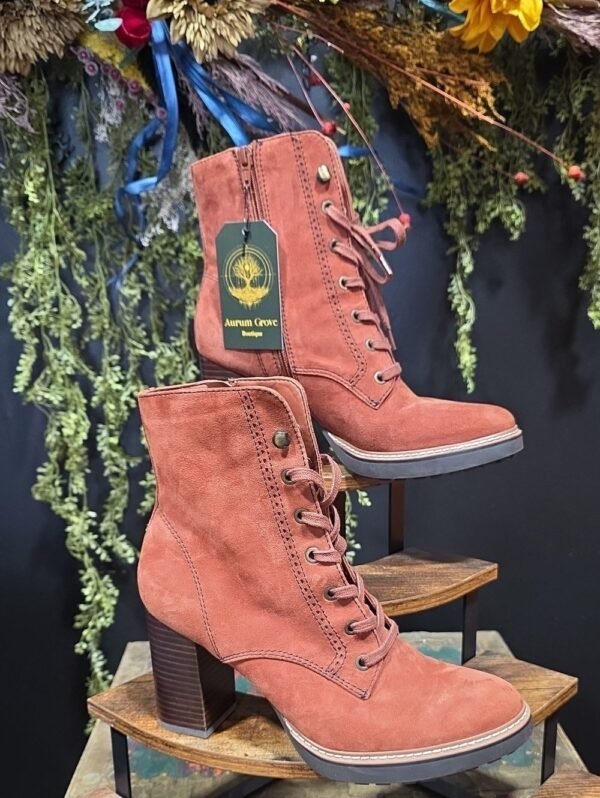 Rust suede lace-up heeled boots on a display stand