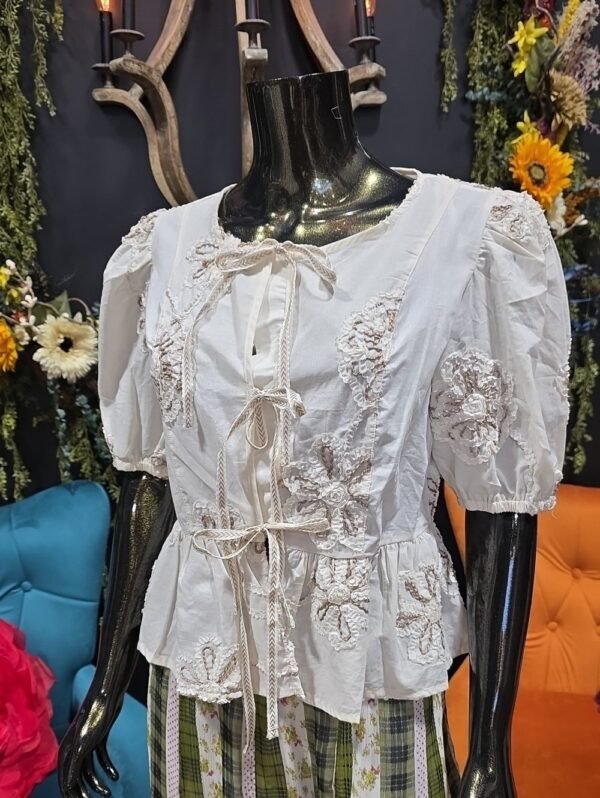 Embroidered off-white tie-front blouse on a mannequin